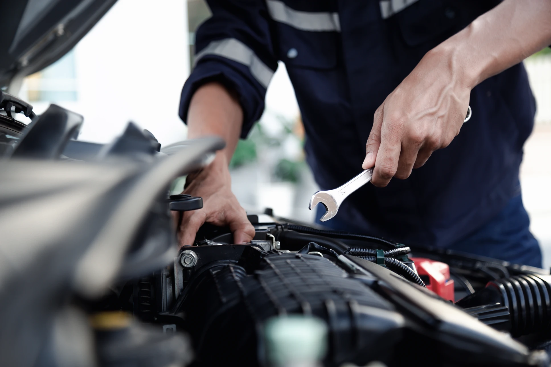 Atelier de réparation automobile avec véhicule blanc surélevé sur pont élévateur hydraulique rouge, capot ouvert pour maintenance